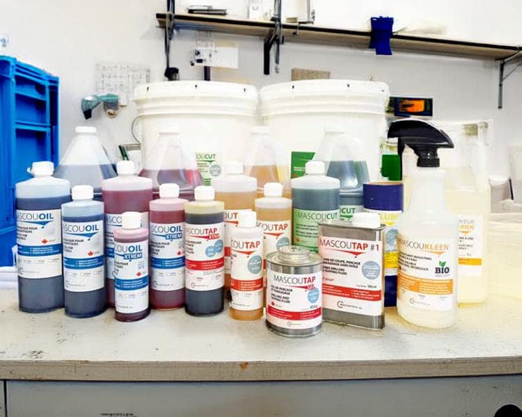 Colorful Mascoutap chemical containers and bottles, labeled in French, neatly arranged on a lab countertop showcasing the full range of Mascoutech's industrial products