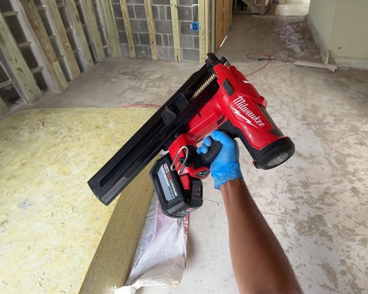 Construction worker demonstrating a battery-powered Milwaukee Nail Gun on a construction site, emphasizing precision and performance
