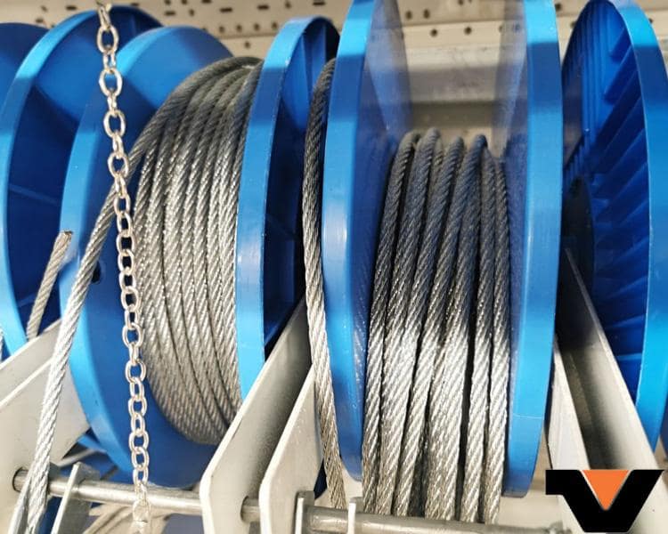 Two blue reels of high tensile strength steel cables made by Vanguard Steel, neatly stored on a warehouse shelf, showcasing durability and strength.